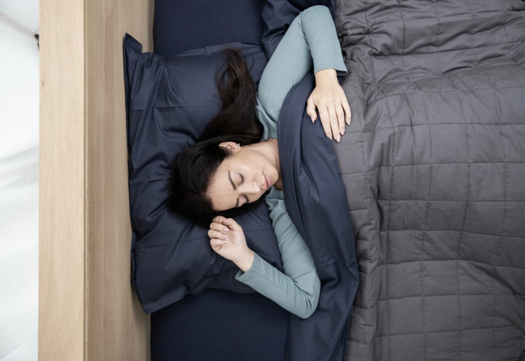Top view of a woman sleeping soundly in bed covered with a comforter