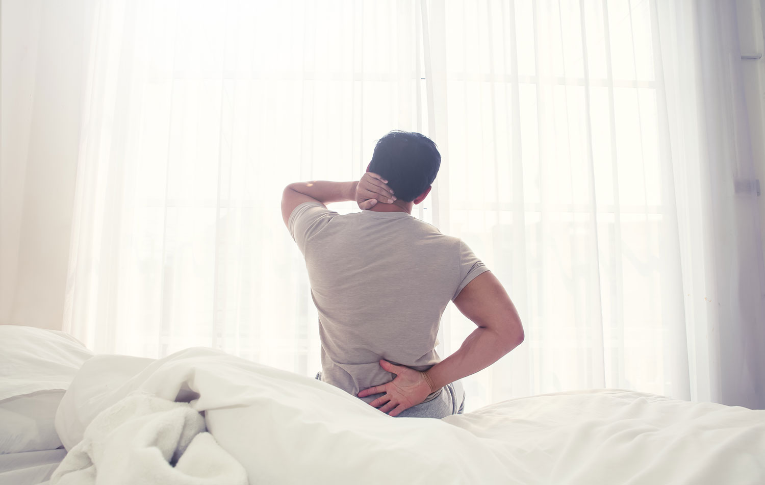 Man waking up from sleep with sore neck and back pain