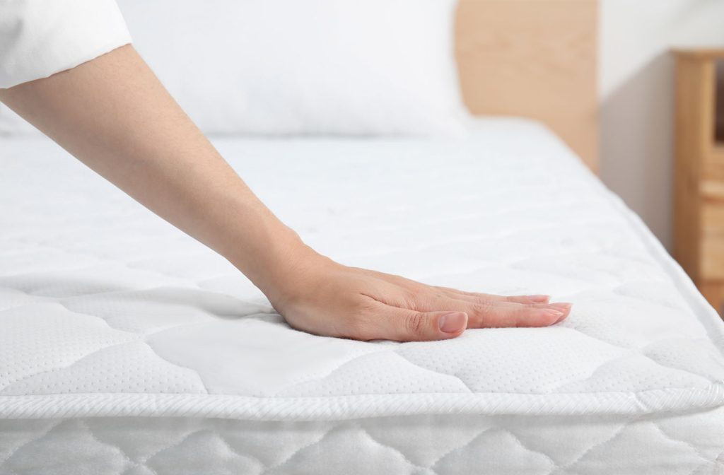 woman touching soft white mattress bed indoors closeup